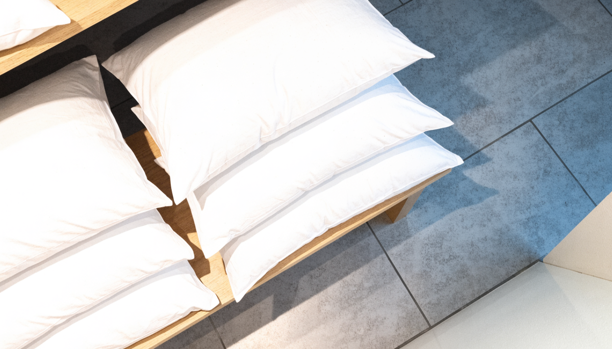 Oreillers blancs empilés sur une étagère en bois clair dans un showroom lumineux